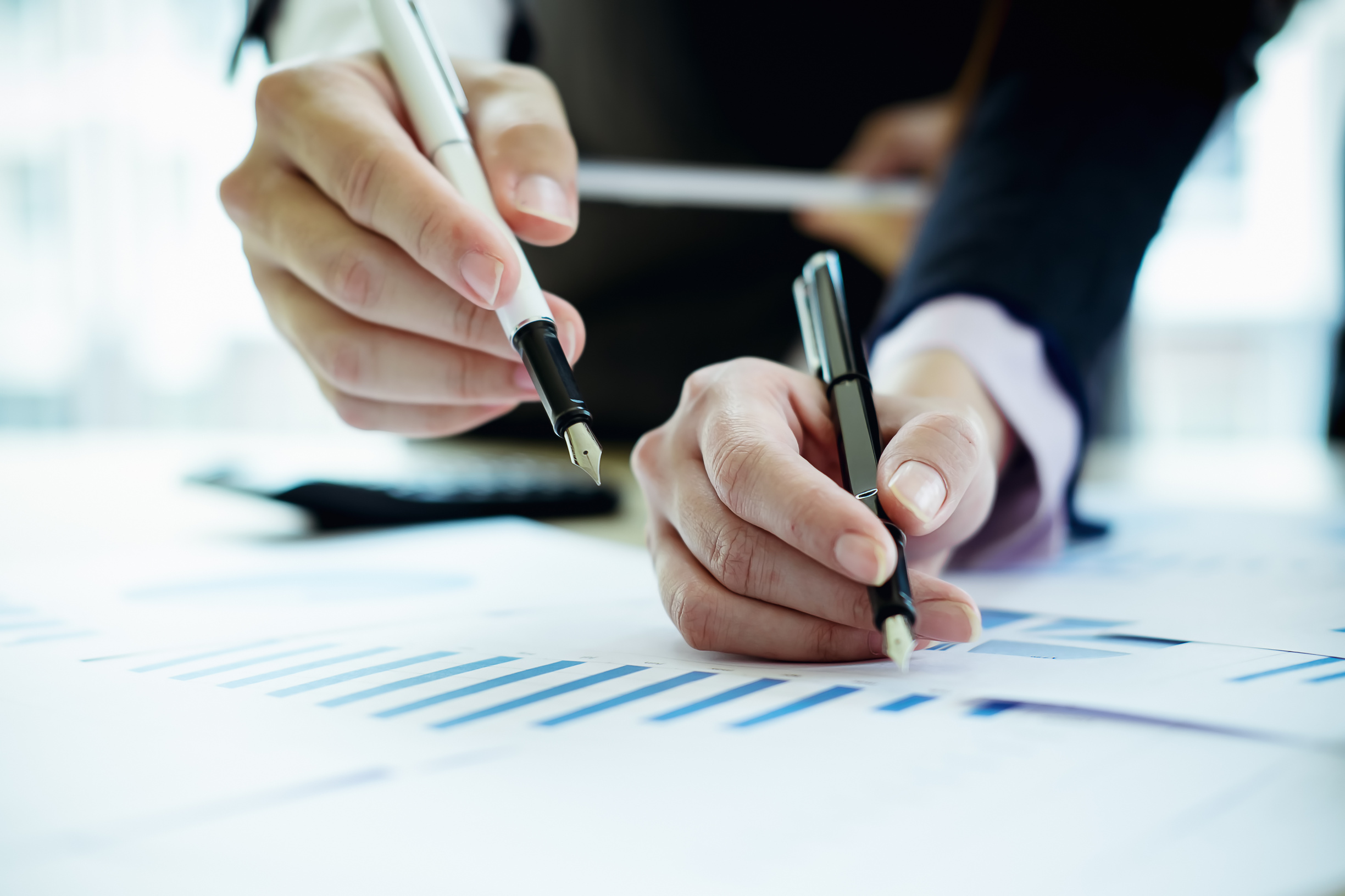 Business Professionals Using Pen to Evaluate Data on Paper